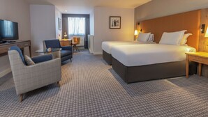 Une chambre d’hôtel avec un grand lit, un bureau, une chaise, une télévision et une petite table.