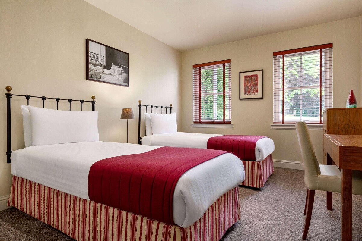 Een hotelkamer met twee bedden, een bureau en een stoel.