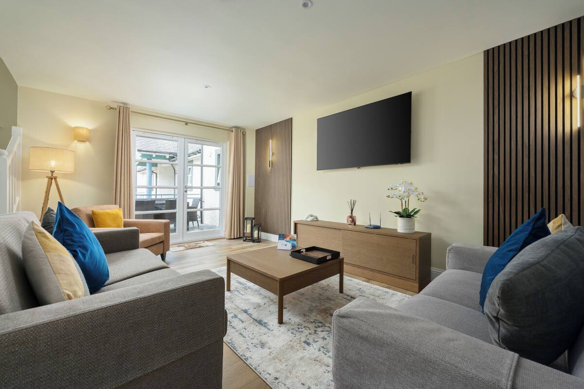 Un salon moderne avec un canapé, une table basse et un téléviseur à écran plat fixé au mur.