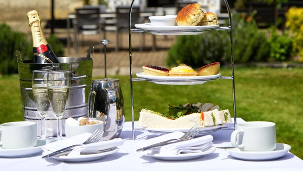 A three-tiered outdoor tea service set on a table with a bottle of champagne, glasses, and a cup. - London Chigwell Prince Regent Hotel, BW Signature Collection (Woodford Green)