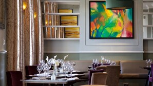 A restaurant with tables set for dining, a colorful abstract painting on the wall, and a modern chandelier. - London Chigwell Prince Regent Hotel, BW Signature Collection (Woodford Green)