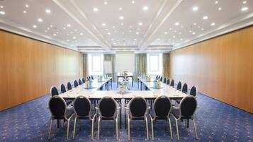 A conference room with a long table, chairs, and a carpeted floor.