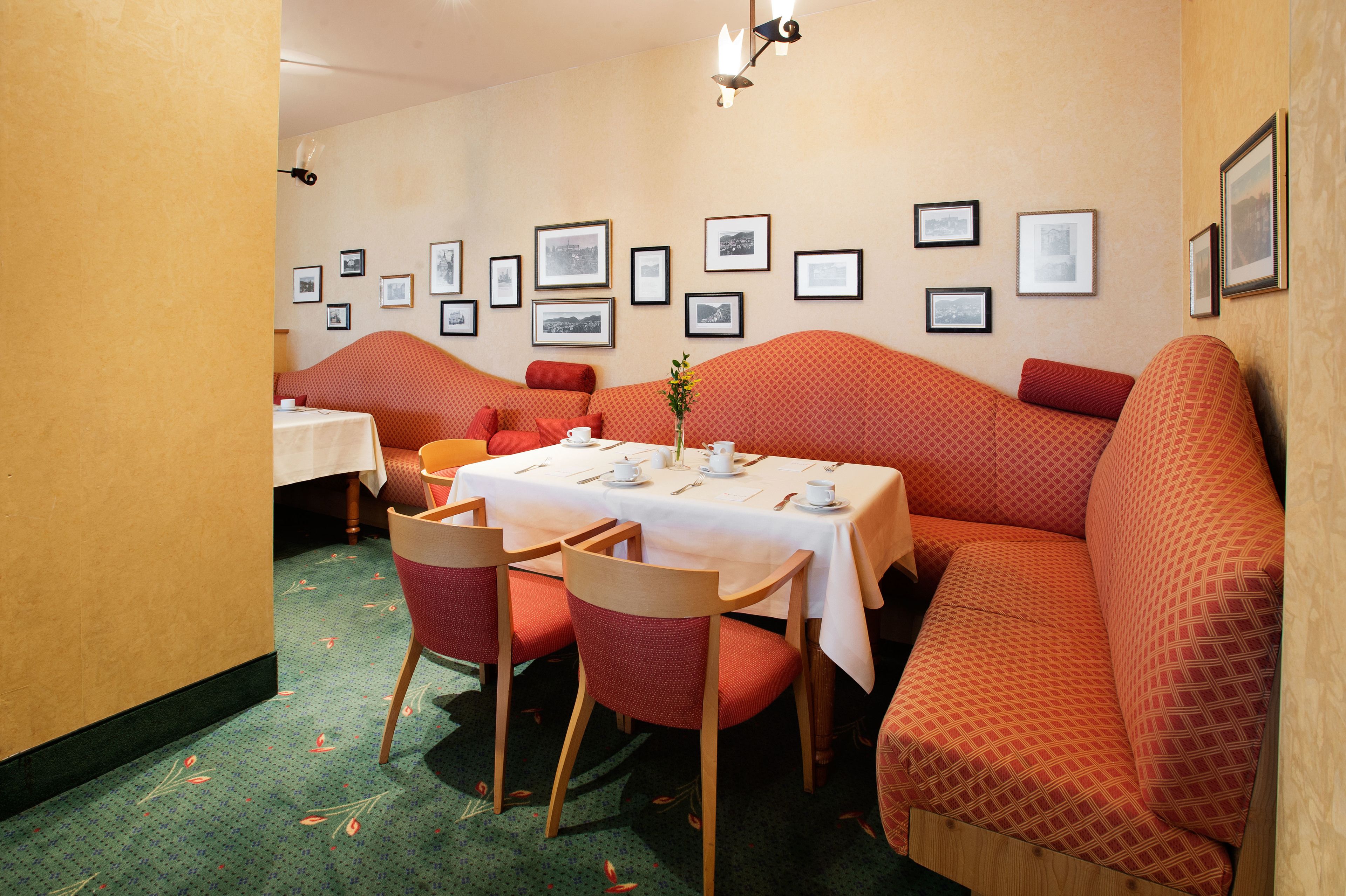 Un comedor con una mesa dispuesta para cuatro personas, rodeado de asientos tapizados en rojo.