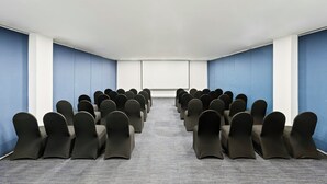 A conference room with rows of chairs, a carpeted floor, and blue walls. - Fiesta Inn Express Perinorte (Tultitlan)