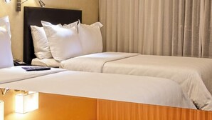 Habitació d'hotel amb dos llits, un capçal i una cortina.