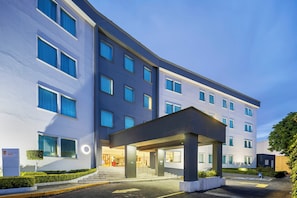 Un hôtel moderne doté d’une entrée couverte, de plusieurs étages et d’une façade bien entretenue.