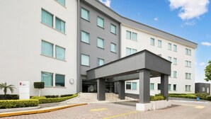 A modern hotel with a covered entrance, multiple floors, and a clear sky. - Fiesta Inn Express Perinorte (Tultitlan)