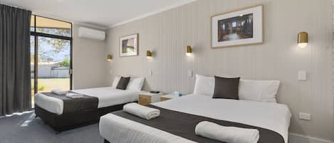 Habitación de hotel con dos camas, un ventanal grande y un cuadro en la pared.