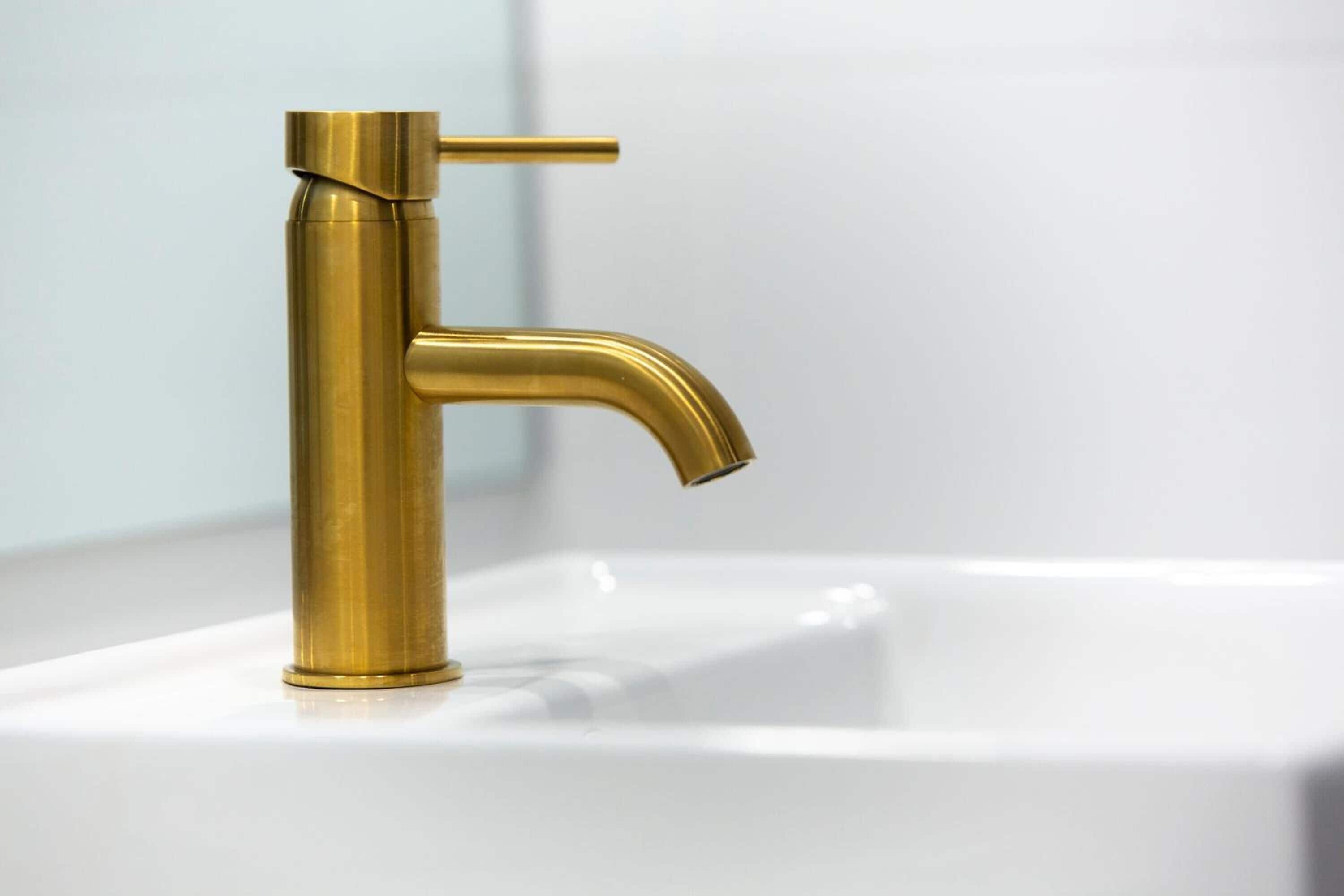 Un grifo dorado sobre un lavabo blanco.