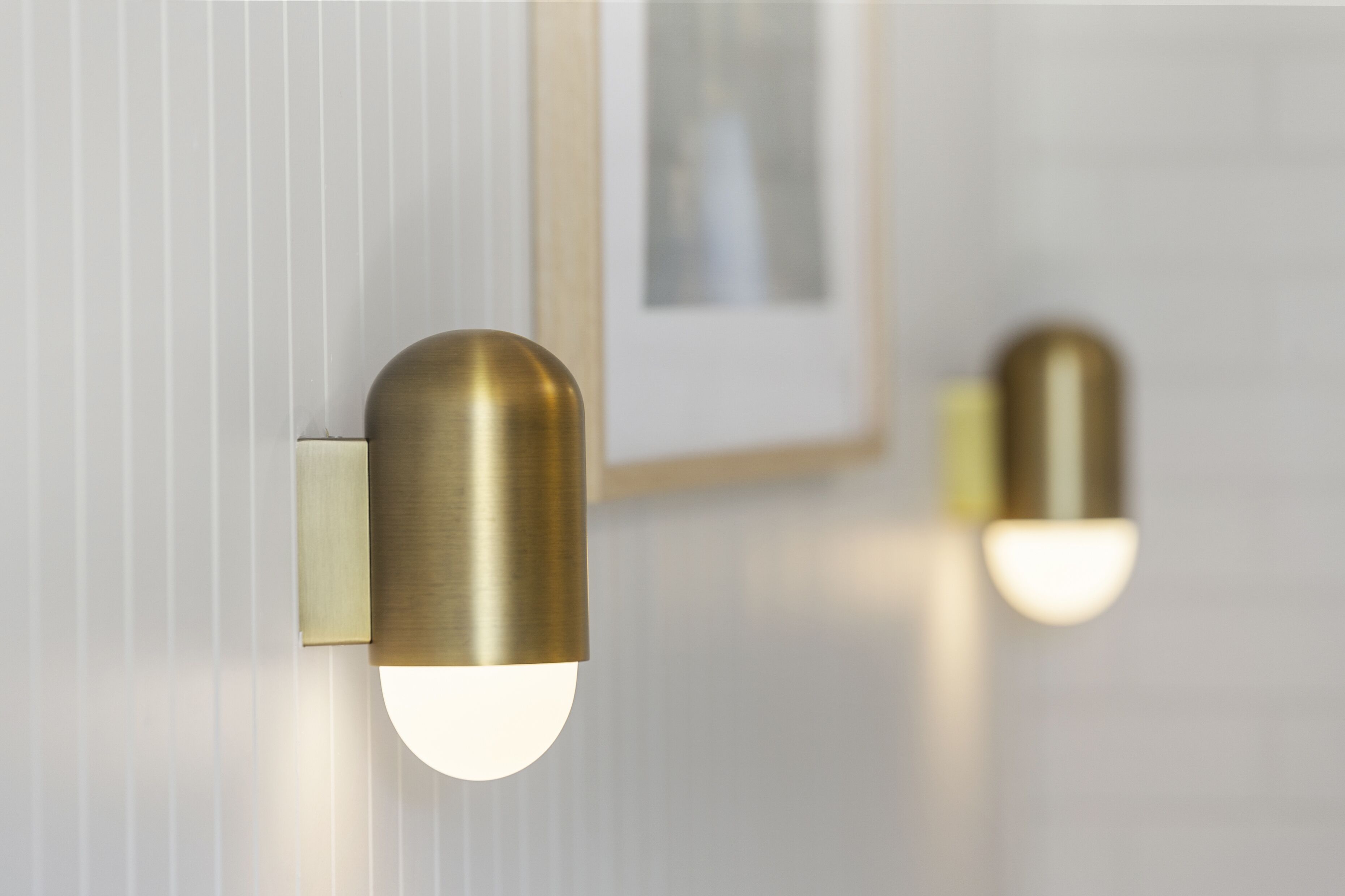 Two wall-mounted lights with a brass finish and white bulbs.