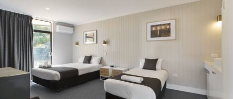 Habitación de hotel con dos camas, un escritorio, una silla y una ventana con cortinas.