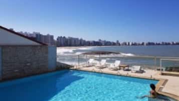Piscina com vista para o oceano e horizonte urbano.