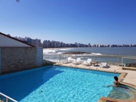 Piscina com vista para o oceano e horizonte urbano.