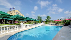 A swimming pool with a white balustrade, green umbrellas, and a Eurotel sign in the background. - Eurotel (Perols)