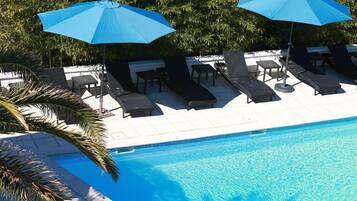 En säsongsöppen utomhuspool och solstolar