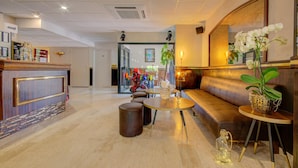 A hotel lobby with a reception desk, seating area, and a large mirror. - Eurotel (Perols)