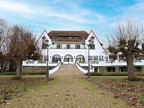 A large, white building with a symmetrical facade, a central staircase, and a stone base.