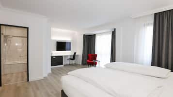 Een moderne hotelkamer met een groot bed, een bureau, een rode stoel en een douche.