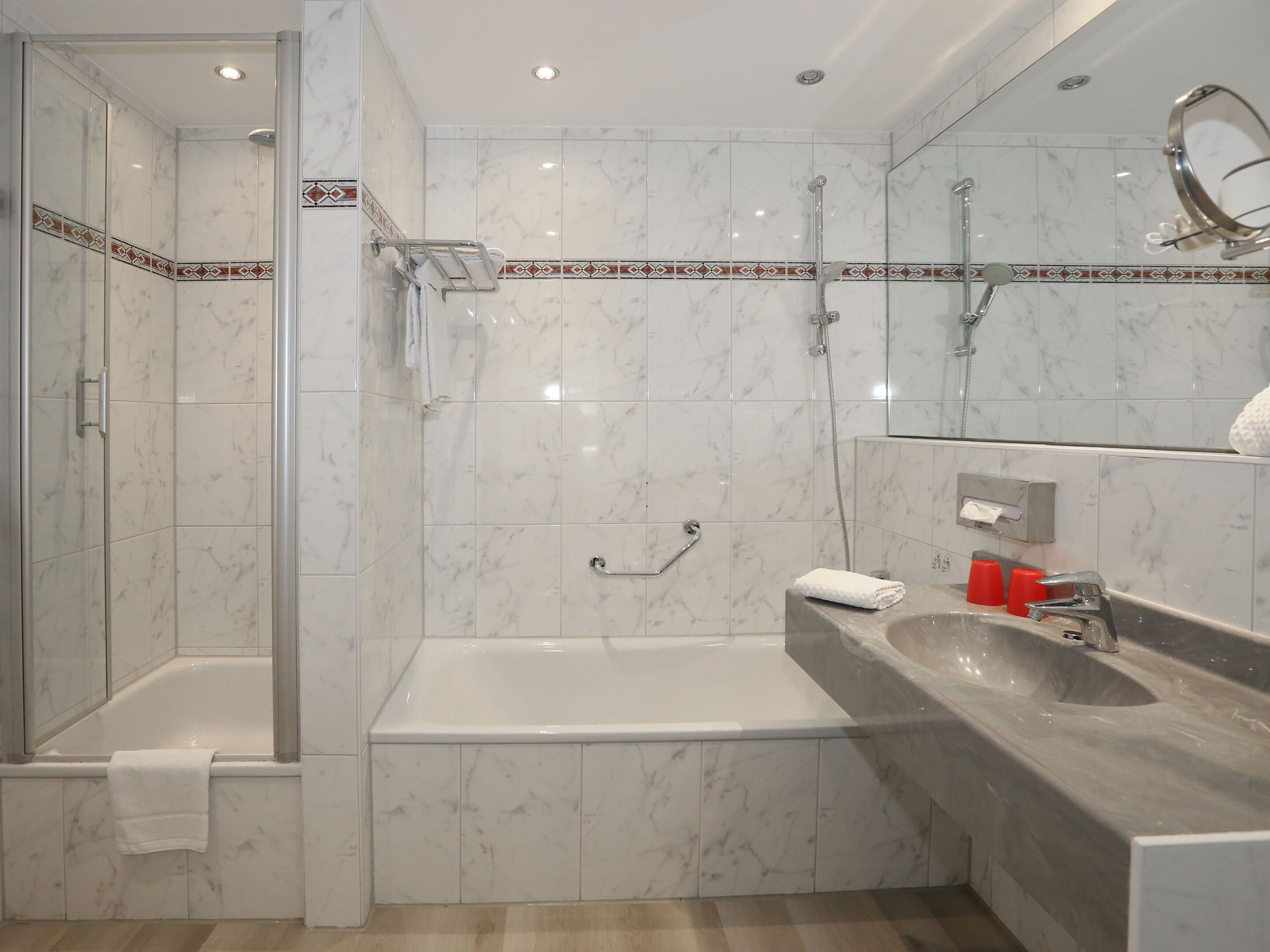 A modern bathroom with a glass-enclosed shower, a standalone bathtub, and a vanity with a sink.