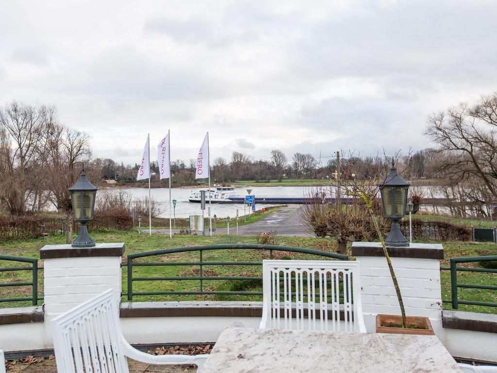 A pathway leading to a body of water with flags, a lamp post, and a bench.