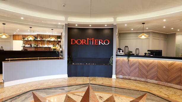A hotel lobby with a reception desk, a bar area, and a decorative floor pattern. - DORMERO Hotel Meerbusch (Meerbusch)