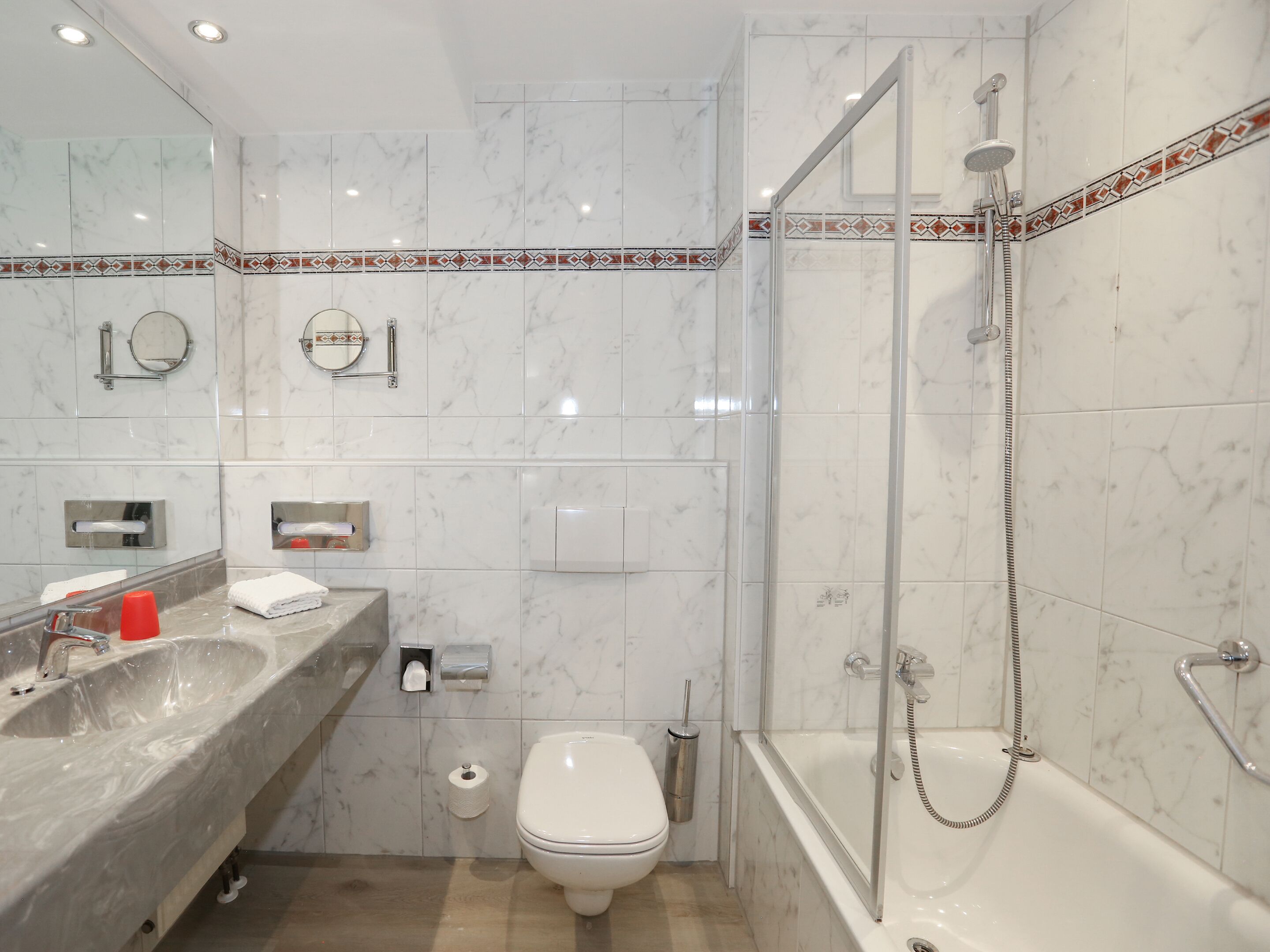 A modern bathroom with a marble sink, toilet, and bathtub.