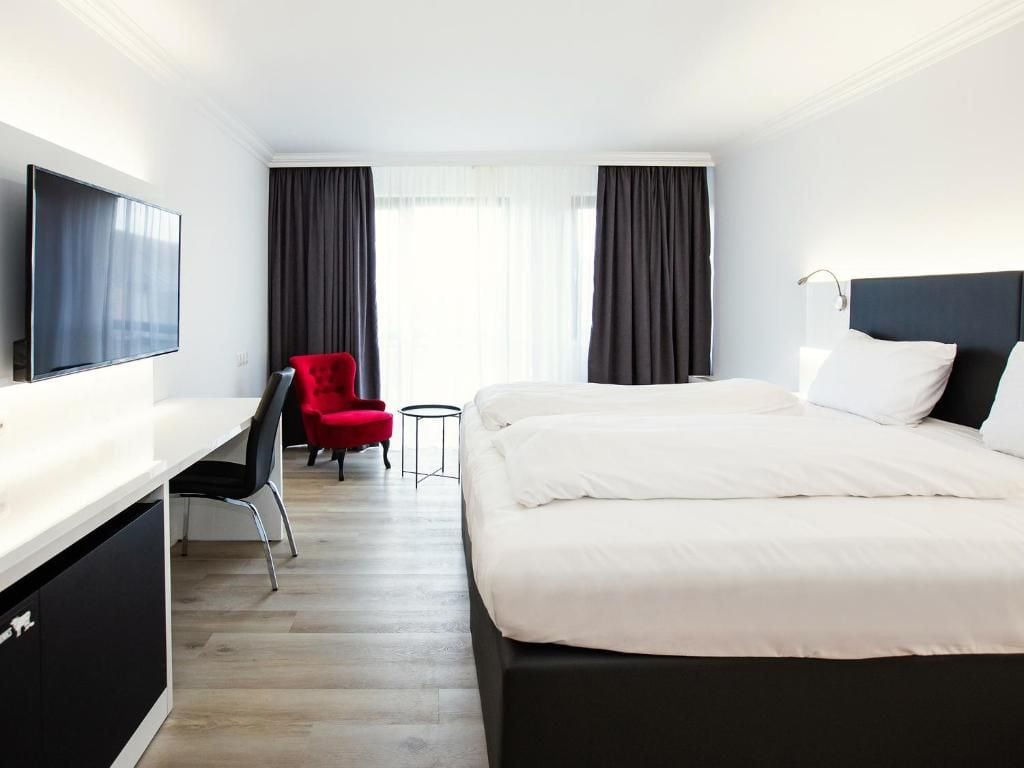 Una habitación de hotel con cama, escritorio, silla y televisor.