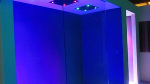 Una habitación con separador de vidrio, luces empotradas en el techo y una puerta visible.