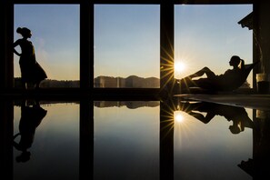 Een kamer met een groot raam dat de zon weerkaatst en de silhouet van een persoon.