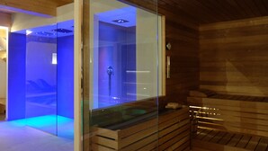 Un cuarto de sauna con separador de vidrio, bancos de madera y una zona de sauna visible con iluminación azul.