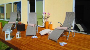 Una terraza con dos sillones, una mesita con un jarrón de flores y dos faroles.