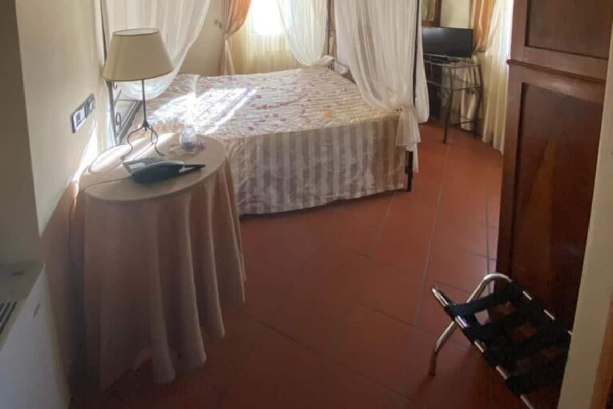 Une chambre à coucher avec un lit à baldaquin, une table de chevet avec une lampe et un fauteuil.