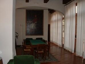Un comedor con una mesa y sillas verdes, un cuadro grande en la pared y vistas al exterior a través de amplias ventanas.