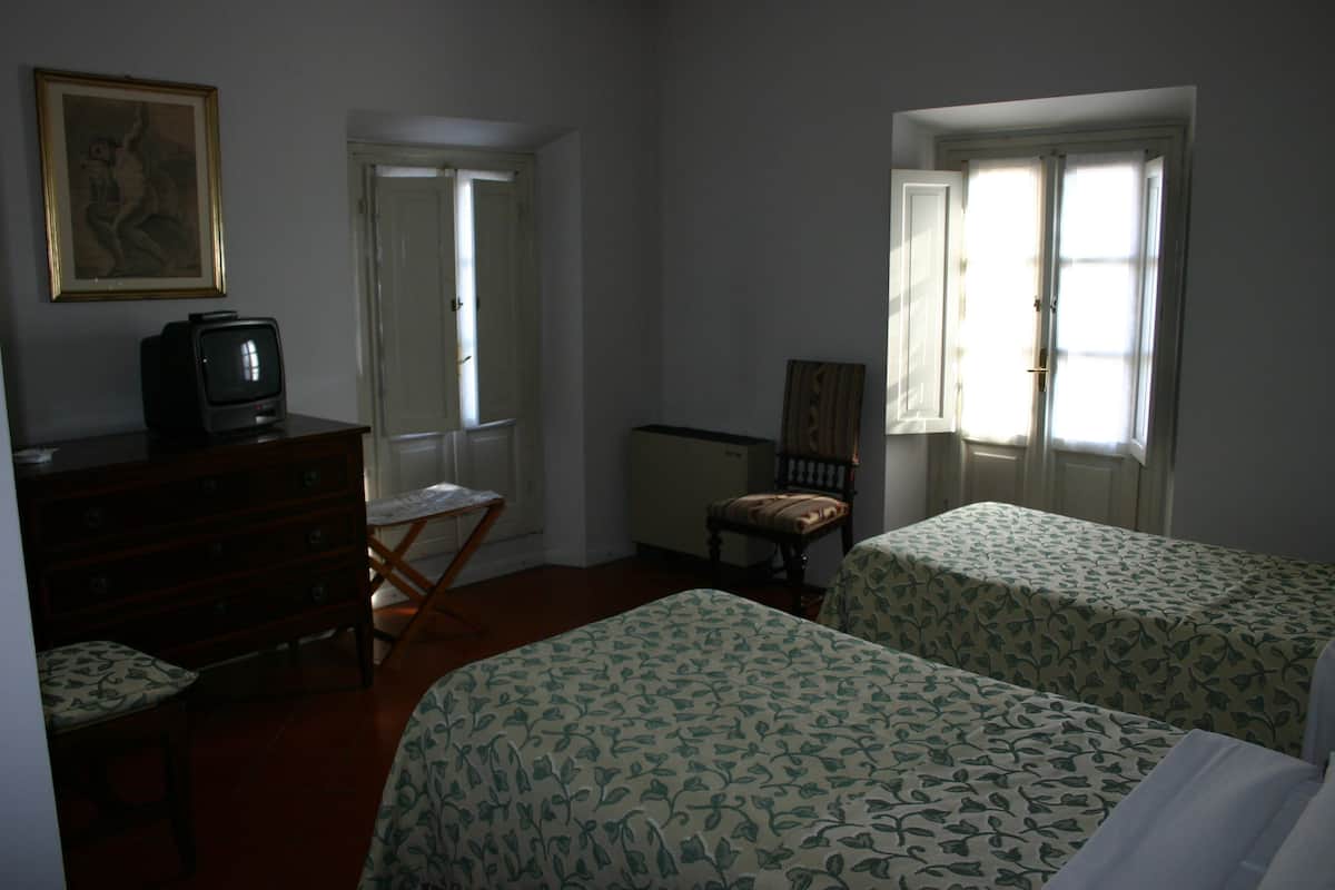 A room with two beds, a dresser, a television, and a chair.