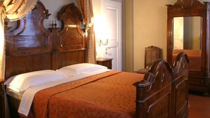Un dormitorio tradicional con una cama de madera, dosel y un espejo grande.
