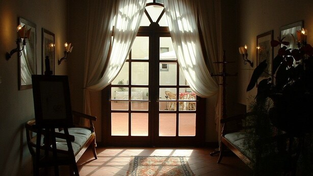 Una habitación con un ventanal grande, una silla, una mesita y una alfombra.