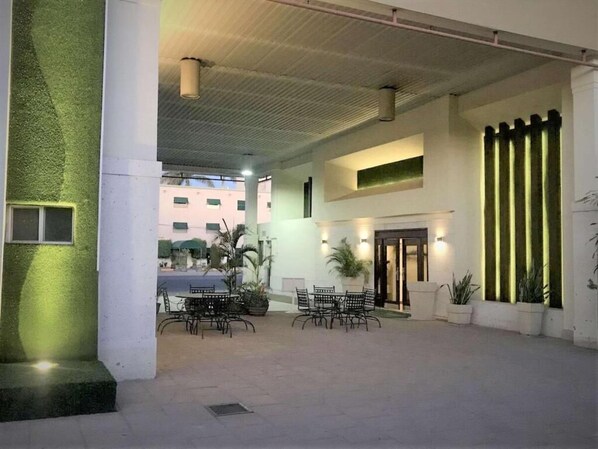 Un patio interior con área de descanso, una escalera y una puerta que da a otra sección.