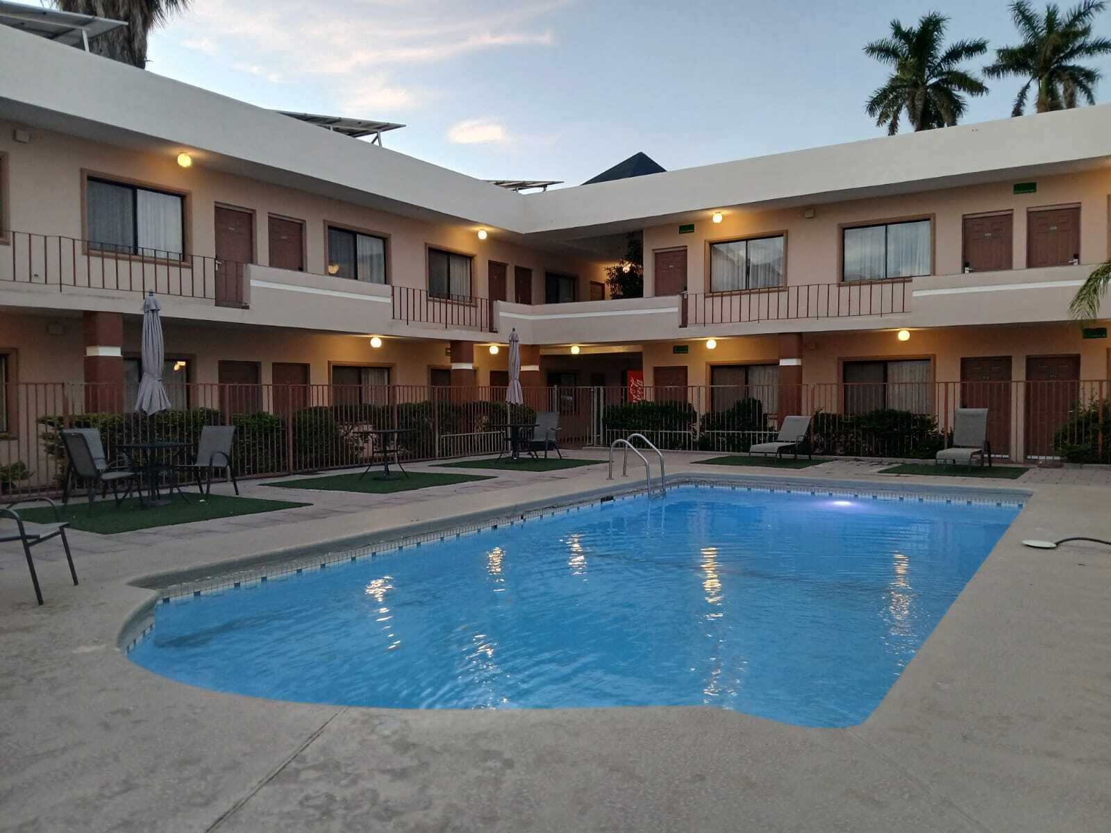 A hotel with a central pool, multiple balconies, and outdoor seating areas.