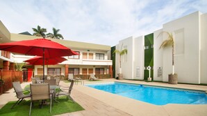 A hotel courtyard with a swimming pool, outdoor seating, and palm trees. - Quality Inn Ciudad Obregon (Cajeme)