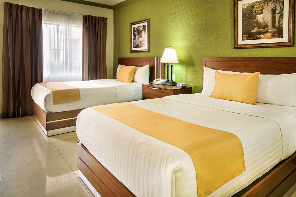 A hotel room with two beds, a nightstand with a lamp, and a painting on the wall.