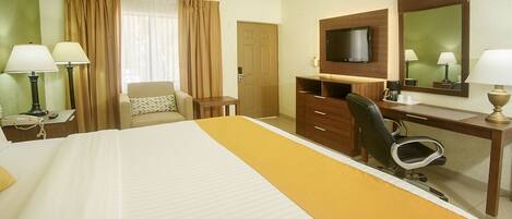 A hotel room with a bed, a desk, a chair, a television, and a mirror.