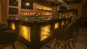 A bar area with a stone wall, a wine rack, and a television. - Quality Inn Ciudad Obregon (Cajeme)
