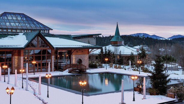 A resort with a pool, stone building, and a church spire.