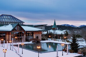 A resort with a pool, stone building, and a church spire.
