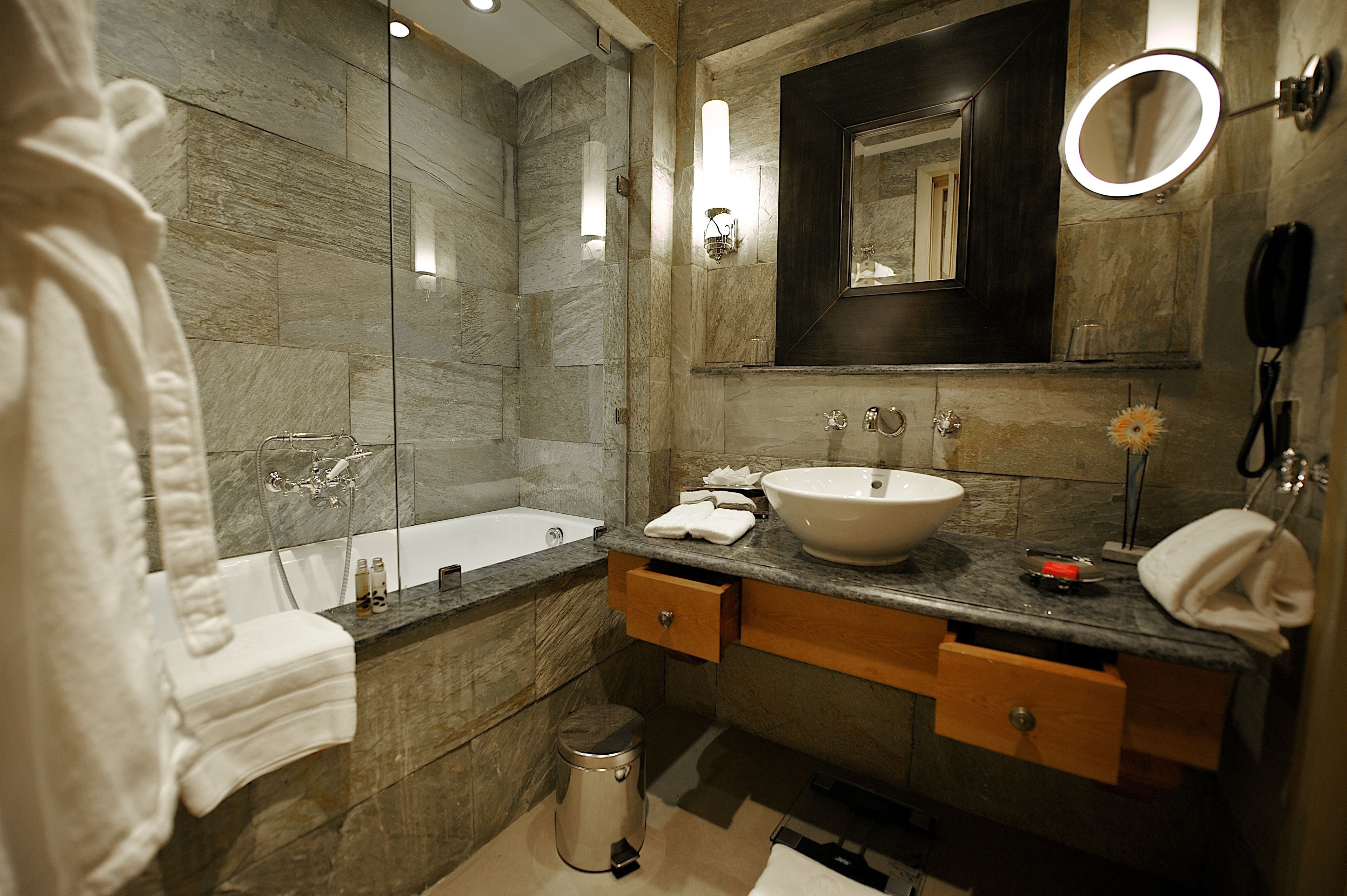 A modern bathroom with a bathtub, a sink, and a mirror. There are towels and toiletries on the counter.