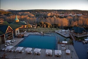 A resort with a large pool, lounge chairs, and a view of a forested area.