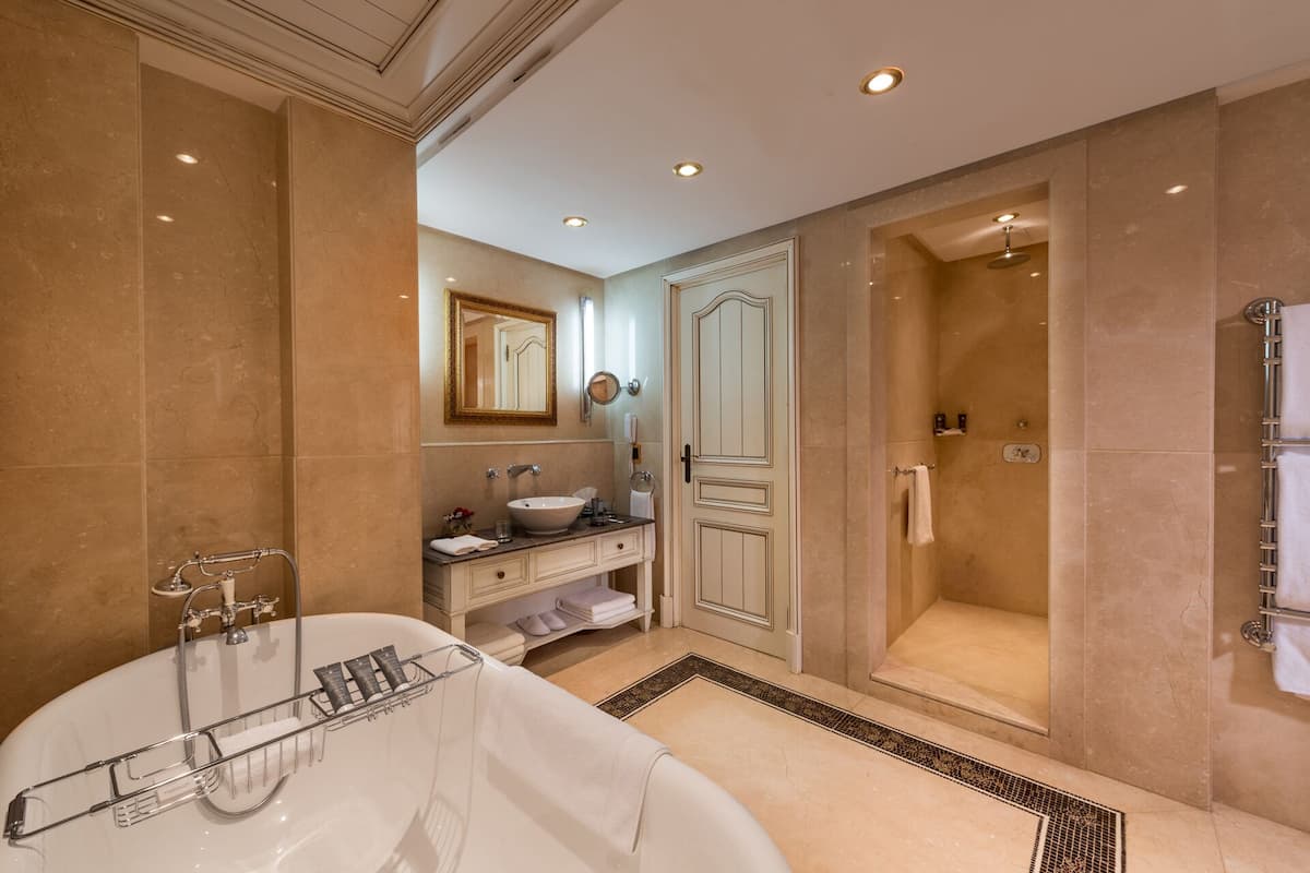 A luxurious bathroom with a freestanding bathtub, a vanity with a sink, a large mirror, and a walk-in shower.