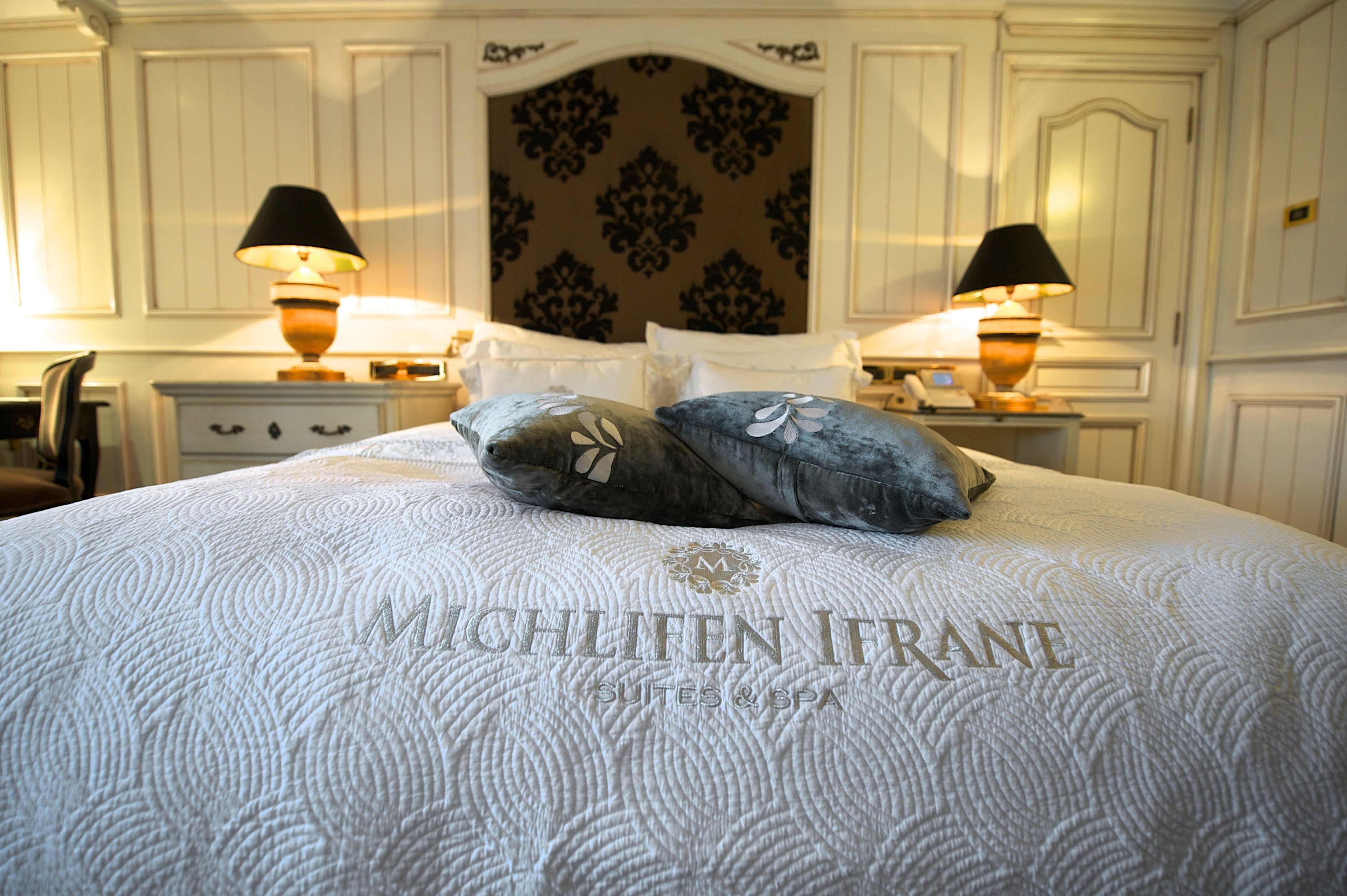 A hotel room with a large bed, two nightstands, and a decorative headboard.