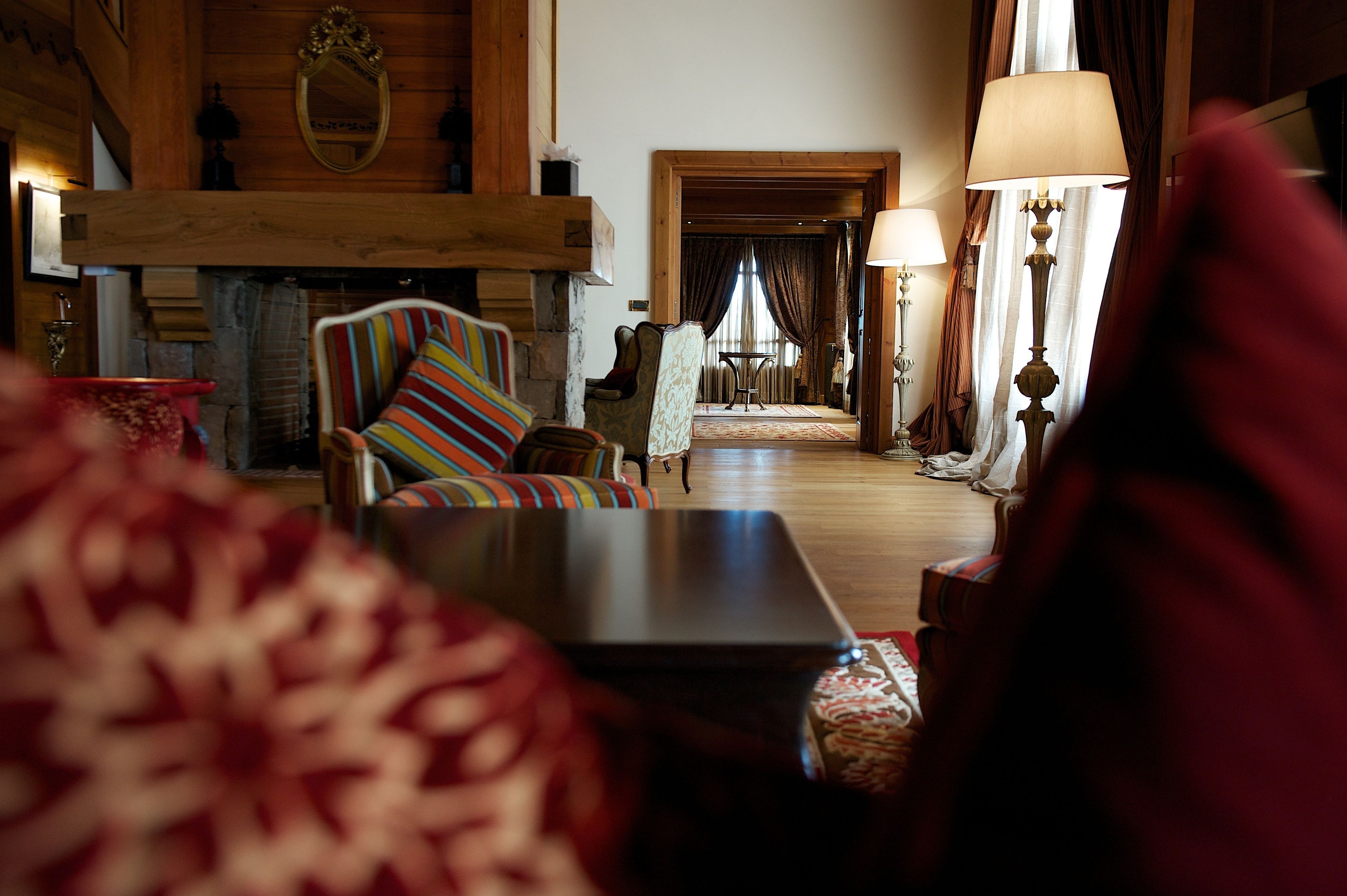 Una sala de estar acogedora con chimenea, un sillón a rayas y una mesita con lámpara.