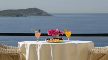 Una mesa con bebidas y fruta, con vista a un cuerpo de agua y una isla distante.